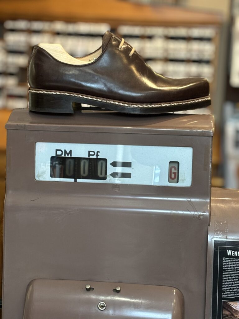 Dunkelbrauner Haferlschuh auf einer alten Registrierkasse Dunkelbrauner Haferlschuh auf einer alten Registrierkasse in der Werkstatt