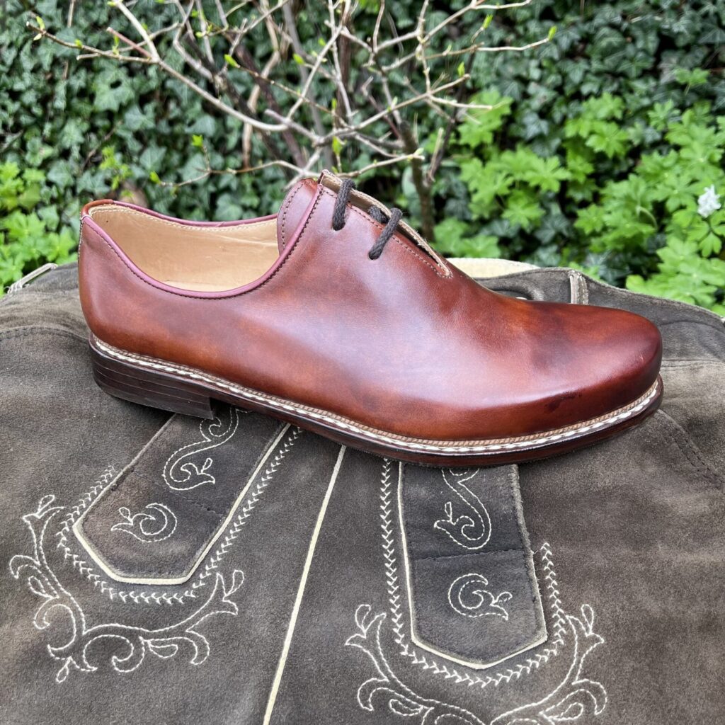 Haferlschuh auf der Lederhose Rotbrauner Haferlschuh auf einer bestickten Lederhose