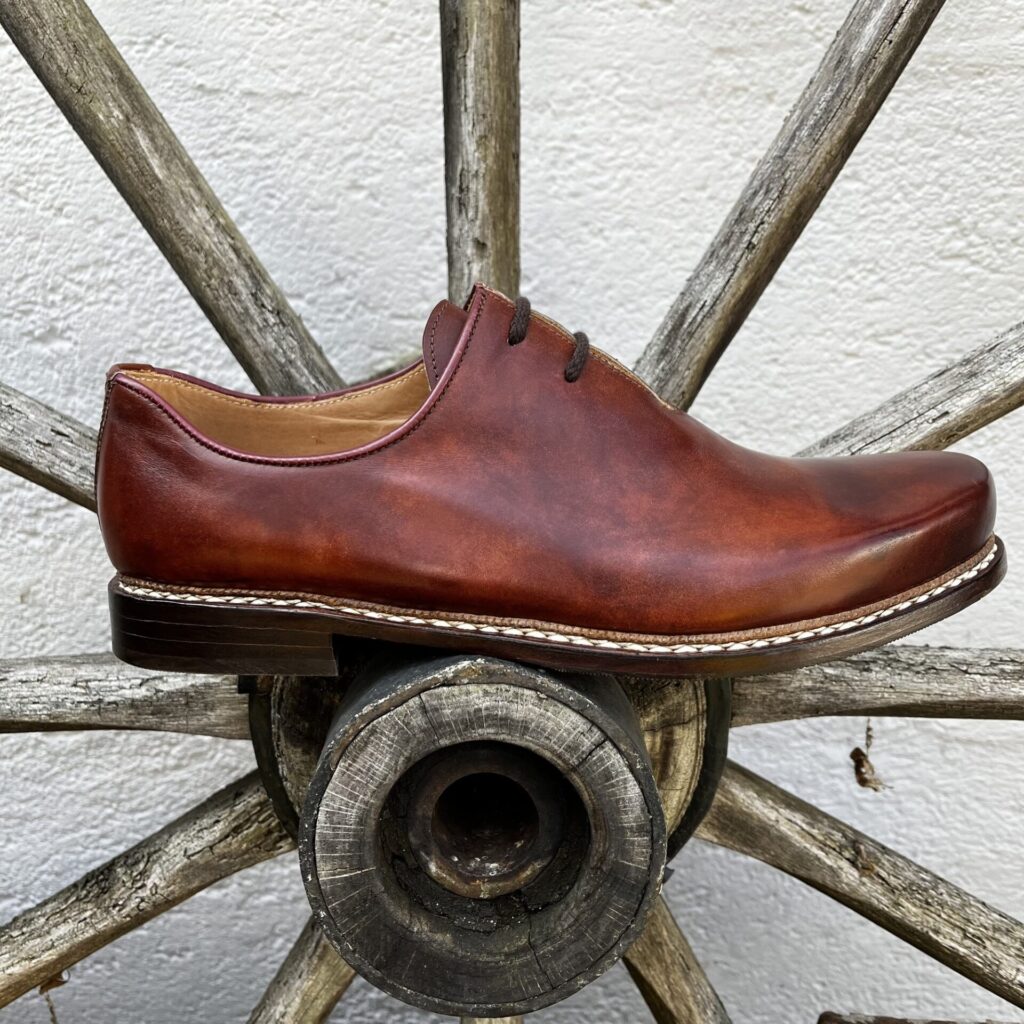 Haferlschuh am Wagenrad Rotbrauner Haferlschuh auf einem alten Wagenrad